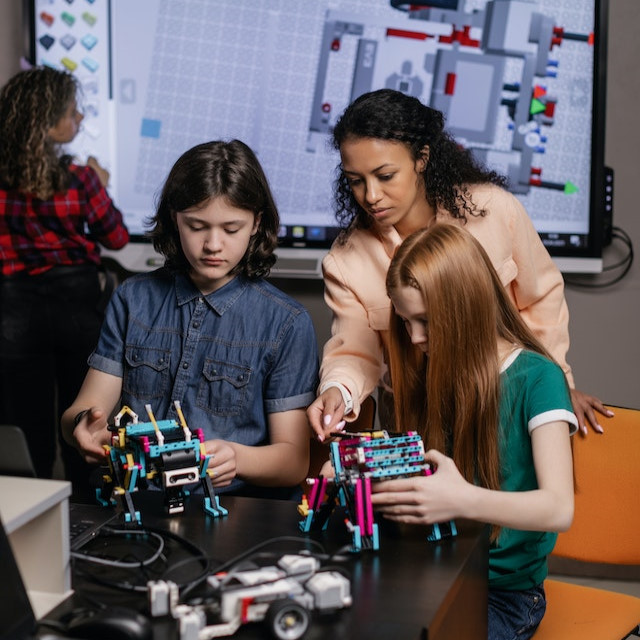woman teaching children how to build a robot